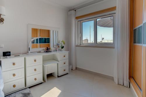 een witte badkamer met een wastafel en een raam bij Carvoeiro Bay Apartment in Carvoeiro