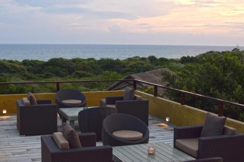 a deck with chairs and tables and the ocean at Jetwing Jungle Lodge, A Luxury Reserve in Yala
