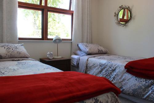 a bedroom with two beds and a window at Entwhistle Cottage in Christchurch