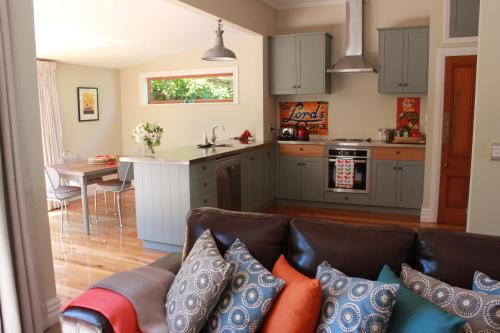 a living room with a couch and a kitchen at Entwhistle Cottage in Christchurch