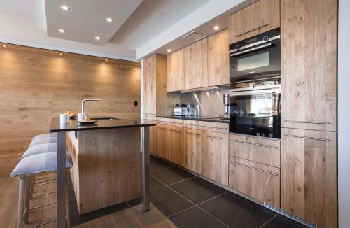 a kitchen with wooden cabinets and a counter top at Hôtel Alparena & Spa - 4 étoiles in La Rosière