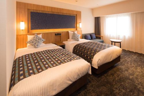 um quarto de hotel com duas camas e uma cadeira em Art Hotel Morioka em Morioka