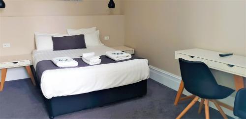 a bedroom with a bed with a desk and a chair at Grand Hotel in Newcastle