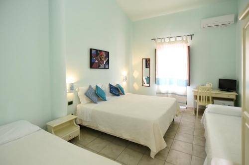 a white bedroom with two beds and a window at Baja Azzurra in Bari Sardo