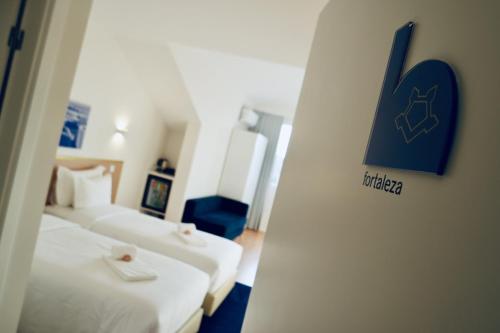 a hotel room with two beds and a sign on the wall at ó Poboa Guesthouse in Póvoa de Varzim