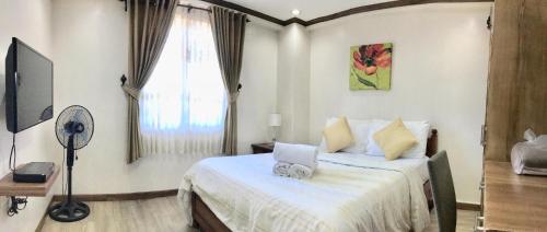 1 dormitorio con 1 cama con sábanas blancas y ventana en Prestige Vacation Apartments - Bonbel Condominium en Baguio