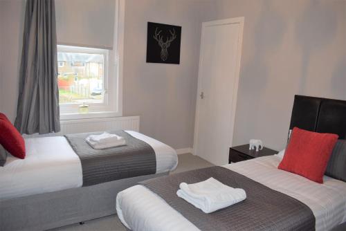 een hotelkamer met 2 bedden en een raam bij Kelpies Serviced Apartments - Wallace in Falkirk