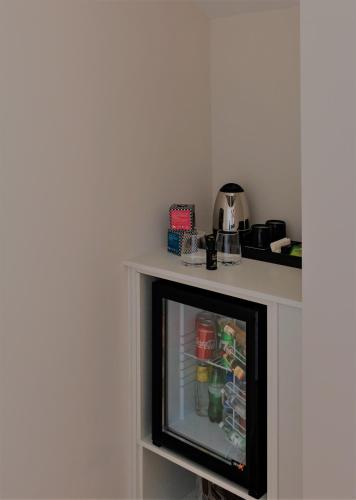 a small tv sitting on a shelf with a refrigerator at ó Poboa Guesthouse in Póvoa de Varzim