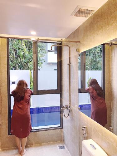 a woman looking out a window in a bathroom at Mưa House in Danang