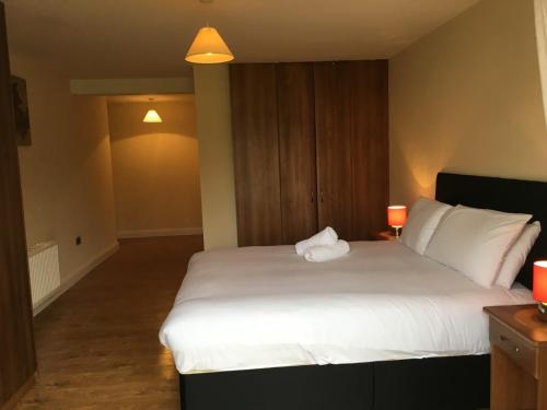 a bedroom with a large white bed with a lamp at Shannon Oaks Apartments in Portumna