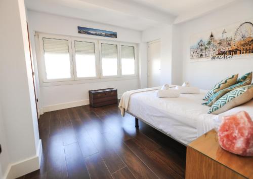 a white bedroom with a large bed and two windows at Malagueta Beach in Málaga