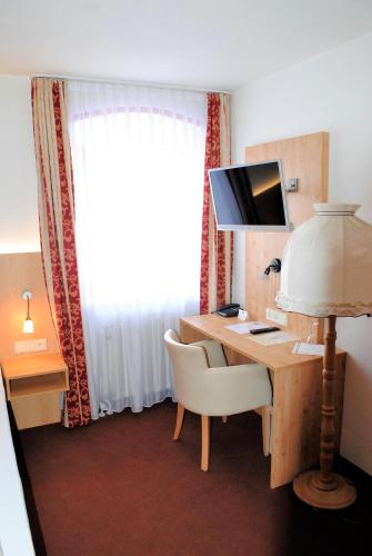 a room with a desk with a computer and a chair at Landgasthof Goldener Pflug in Frasdorf