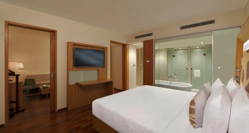 a bedroom with a white bed and a bathroom at Novotel Chennai OMR in Chennai