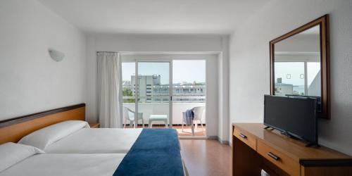1 dormitorio con cama, espejo y TV en Hotel Foners en Playa de Palma