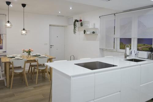 a white kitchen with a sink and a table at Foncalada 13 in Oviedo