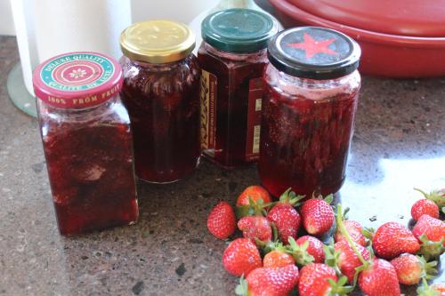 three jars of strawberry jam next to a pile of strawberries at The Summit Lodge in Gladstone