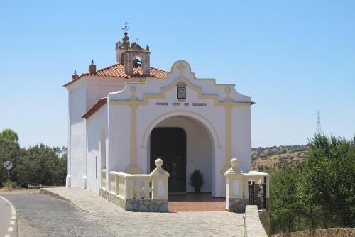 a small white church with a clock tower on a street at LA POSADA in Medina de las Torres