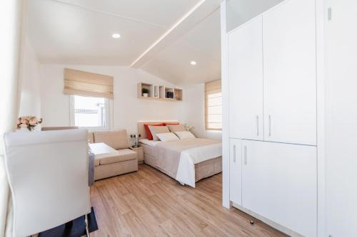 a white bedroom with a bed and a couch at Tannisby Camping in Tversted