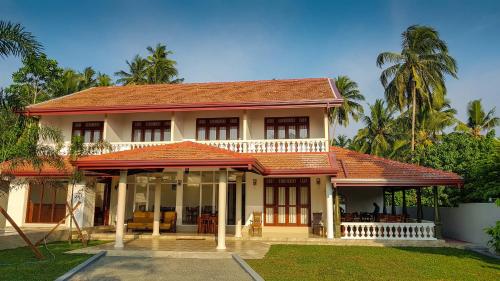 une maison avec un toit rouge et des palmiers dans l'établissement Turtle Paradise Villa, à Kosgoda