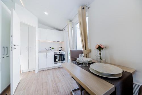 a kitchen with white cabinets and a wooden table at Tannisby Camping in Tversted