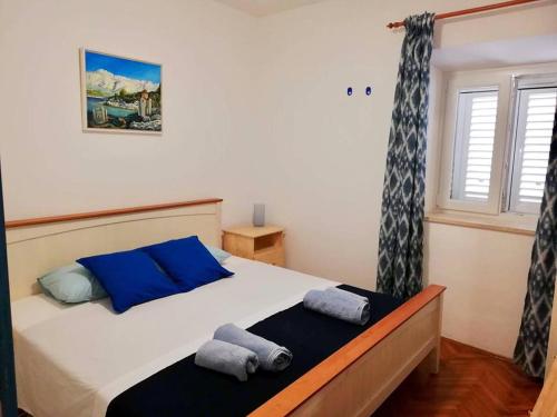 a bedroom with a bed with blue pillows and a window at Puntin Rooms Sobe in Korčula