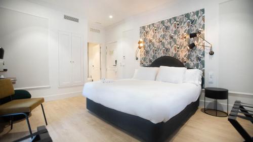 a bedroom with a large white bed and a chair at Soho Boutique Opera in Madrid
