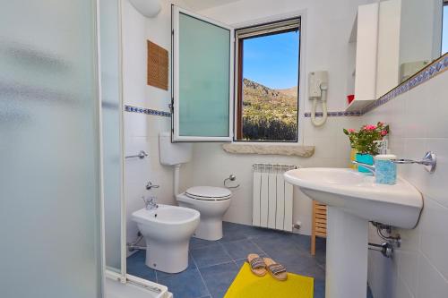 a bathroom with a sink and a toilet and a window at Villa Gaia - Scopello-Villas in Scopello