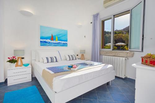 a white bedroom with a bed and a window at Villa Gaia - Scopello-Villas in Scopello
