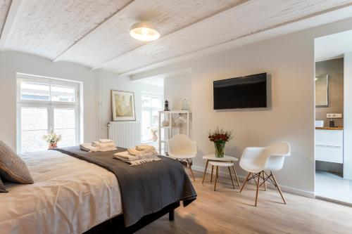 a bedroom with a large bed and two white chairs at B&B Gracht 62 in Maastricht
