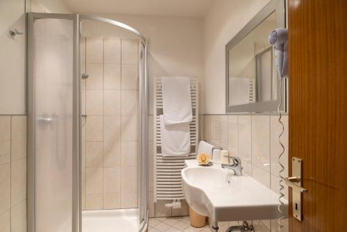 a white bathroom with a sink and a shower at Sporthotel Spoegler in Collalbo