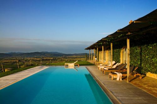 a pool with chairs and a house with a view at Wine Resort Conti di San Bonifacio in Montemassi