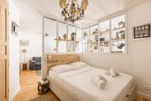 une chambre avec un lit avec des draps blancs et un lustre dans l'établissement Veeve - À la Mode Retreat by the Seine, à Paris