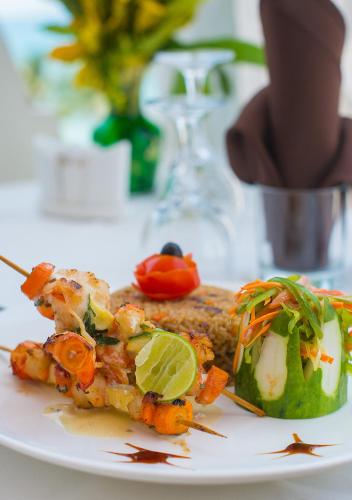 a plate of food with a piece of fish and a pickle at The Seyyida Hotel and Spa in Zanzibar City