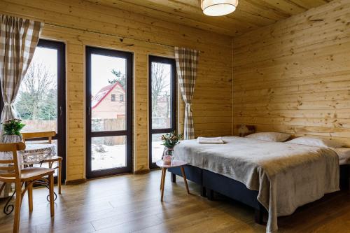 a bedroom with a bed in a wooden room with windows at Villa Bezycer in Gowidlino