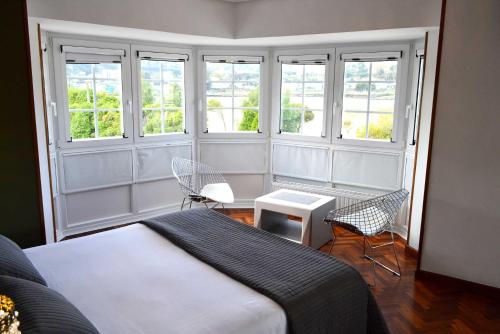 a bedroom with a bed and two chairs and windows at Hotel Alda Santa Cristina in Perillo