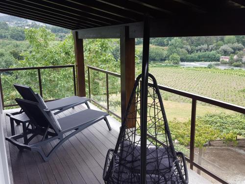 a rocking chair on a porch with a view of a vineyard at Quinta do Burgo - Nature Hotel in Amares