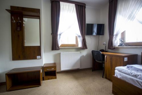 1 dormitorio con cama, escritorio y espejo en Hotel Chańcza en Raków