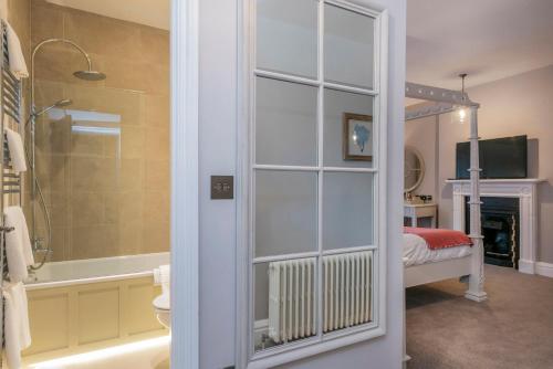 a bathroom with a shower and a tub and a bedroom at Heacham Manor Hotel in Hunstanton