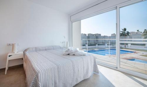 Dormitorio blanco con cama y ventana grande en Eulalia Apartments, TarracoHomes, en Altafulla