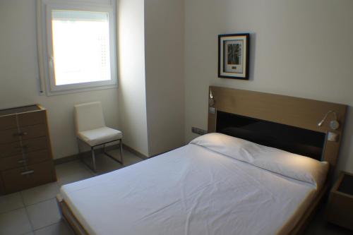 a bedroom with a bed and a chair and a window at Agi Drugstore Apartments in Roses