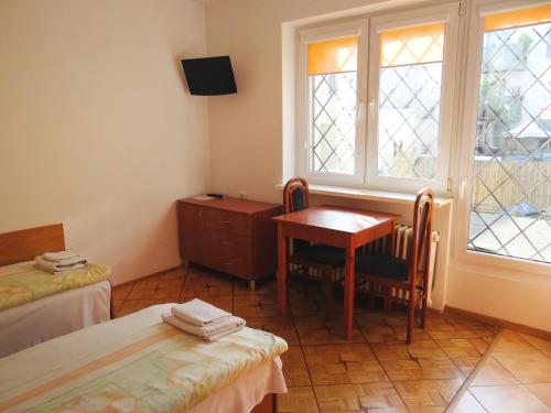 Zimmer mit 2 Betten, einem Tisch und einem Fenster in der Unterkunft Willa Ewa in Warschau