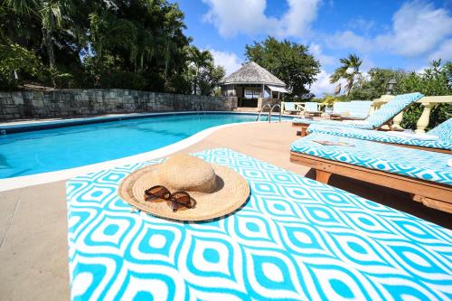 a straw hat on a bed next to a swimming pool at The Great House in Saint Peter