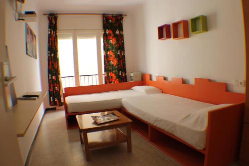 a bedroom with two beds and a table and a window at Agi Sant Antoni in Roses