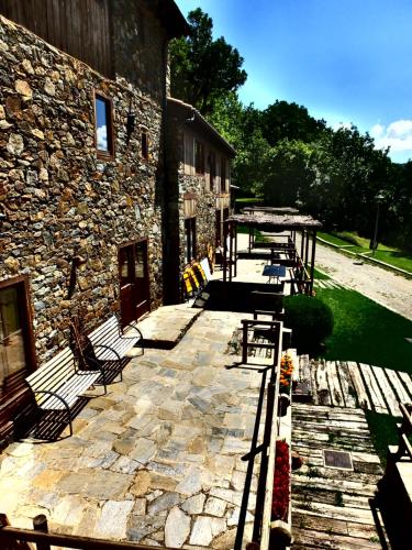 a patio with benches next to a stone building at El Serrat Turisme Rural in Planoles