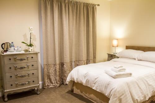 a bedroom with a bed and a dresser with towels on it at Fair Oak House Exeter Airport in Exeter