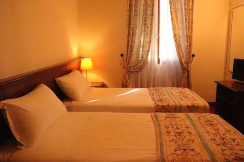 a hotel room with two beds and a window at Meditur Hotel Bologna in Bologna