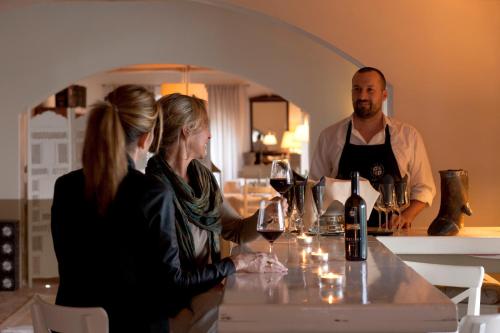 a man and two women sitting at a table with wine glasses at Wine Resort Conti di San Bonifacio in Montemassi