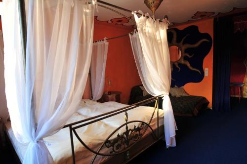 a bedroom with a canopy bed with white curtains at Hotel Goldflair am Rathaus in Korbach
