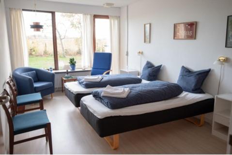 um quarto com 2 camas com almofadas azuis e uma cadeira em Shalom em Gjerlev