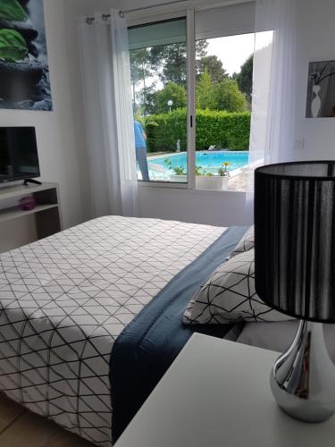 1 dormitorio con cama y vistas a la piscina en Chambre Indépendante "Terre Rouge", en Martignas-sur-Jalle